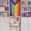 A Pride Flag surrounded by bookshelves.
